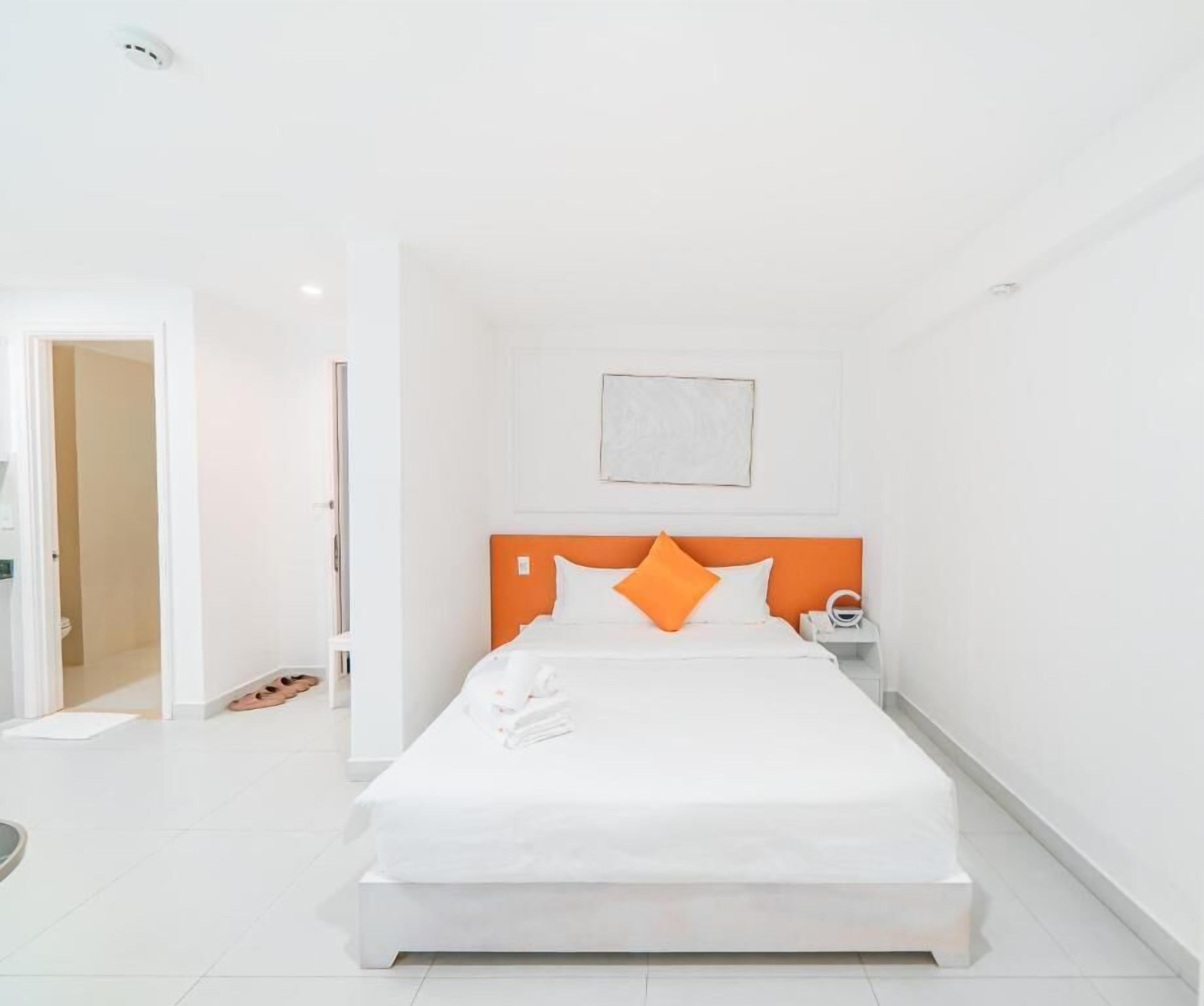 A modern hotel room with a large bed, a nightstand, and a door leading to another room.