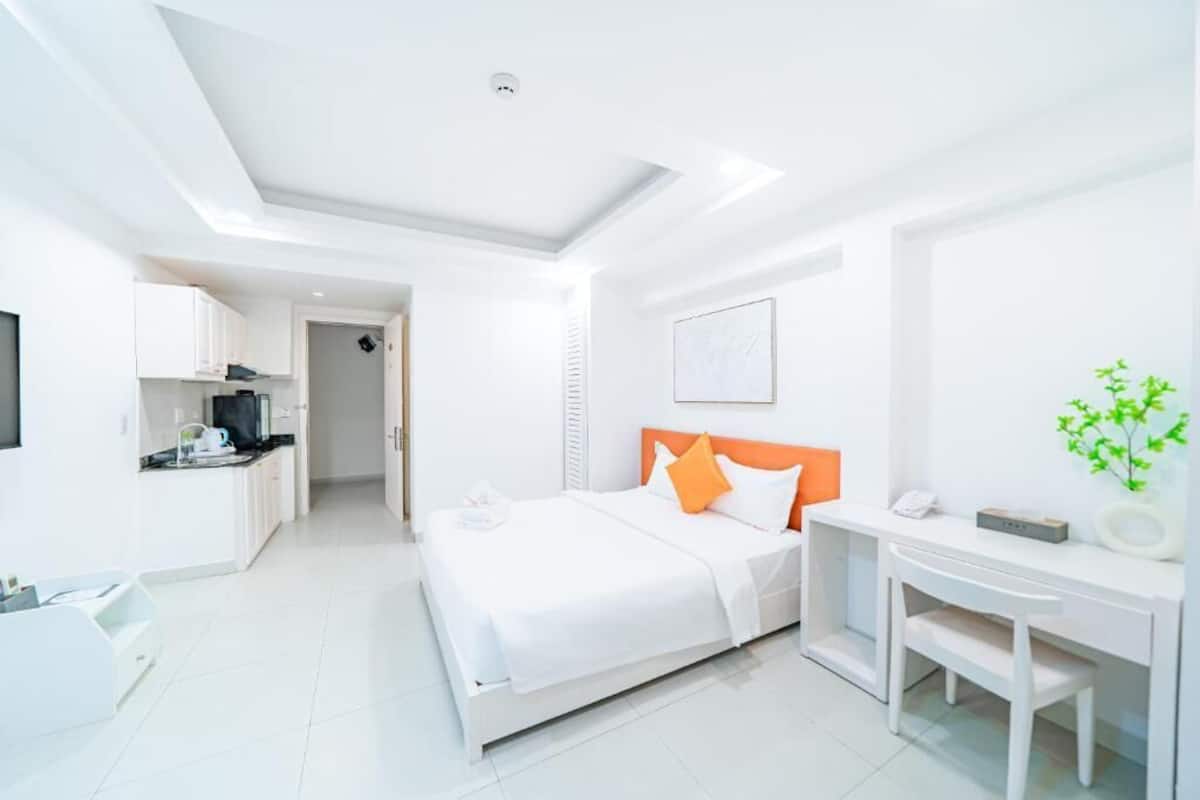 Une chambre d’hôtel moderne équipée d’un lit, d’un bureau, d’une chaise, d’une petite kitchenette et d’une salle de bain.