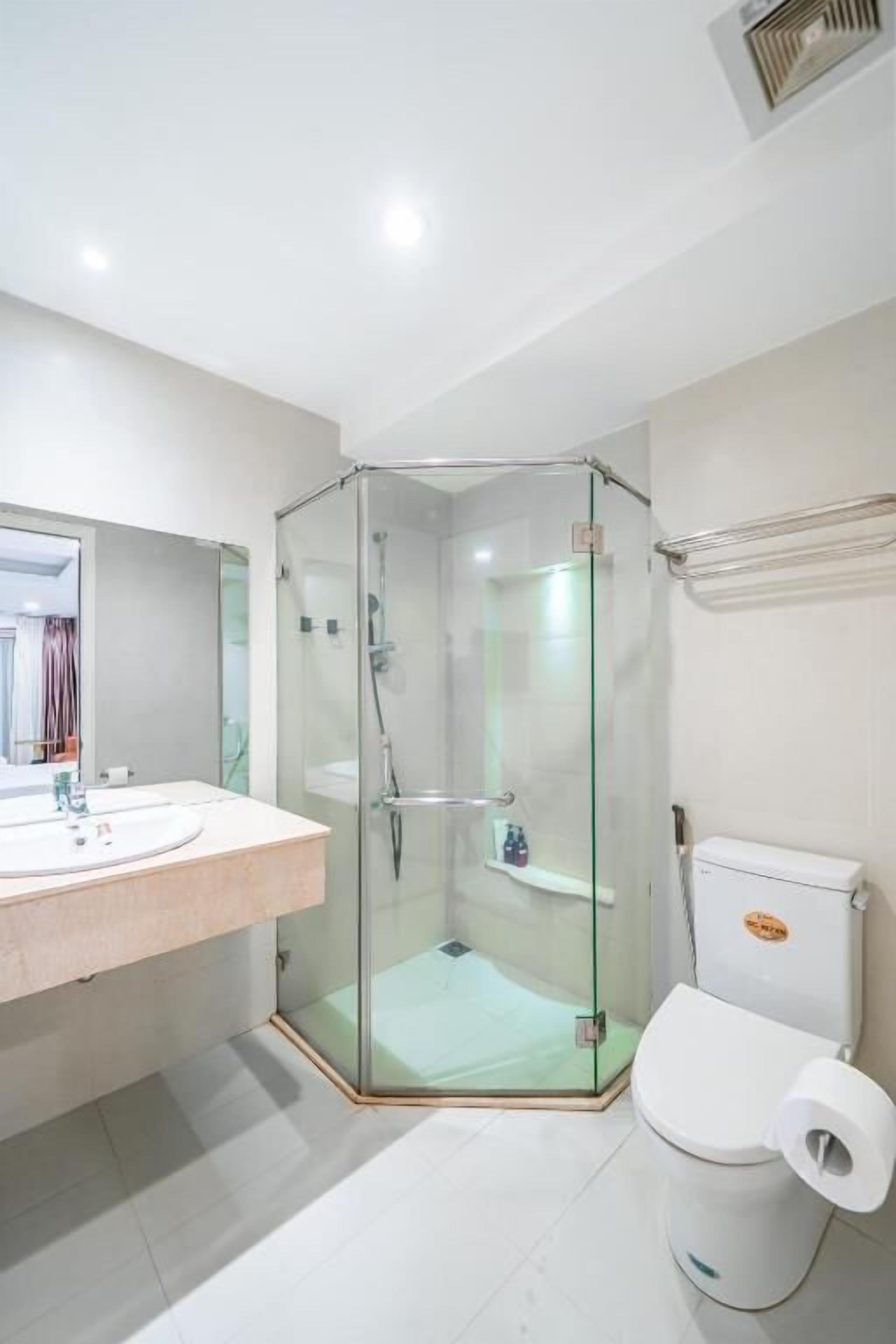 A modern bathroom with a glass-enclosed shower, a white sink, and a toilet.