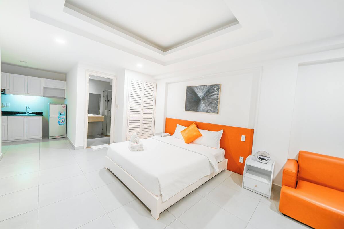 Une chambre d’hôtel moderne comprenant un lit, une table de chevet, un canapé, un coin cuisine et une salle de bain.