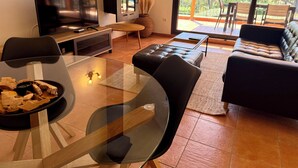 Una sala de estar moderna con una mesa de vidrio, sofá de cuero y televisor.