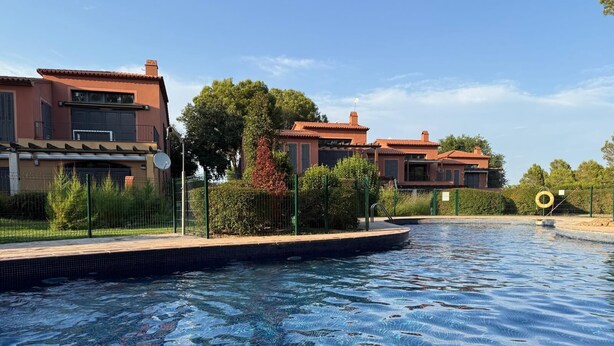 Una piscina con agua cristalina, rodeada de una cerca y árboles.