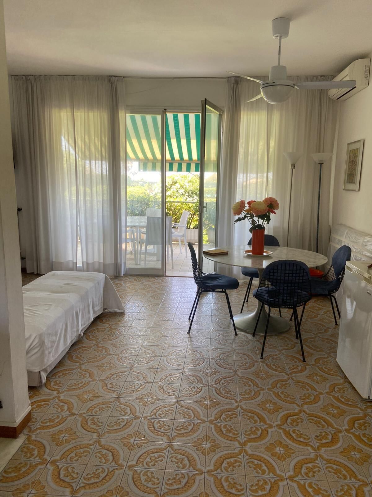 Une pièce comprenant un lit, une table à manger avec des chaises, un ventilateur de plafond et une vue sur l’extérieur, visible à travers une porte vitrée.