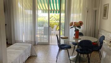 Une pièce comprenant un lit, une table à manger avec des chaises, un ventilateur de plafond et une vue sur l’extérieur, visible à travers une porte vitrée.
