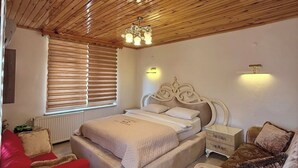 Un dormitorio con techo de madera, una cama con cabecera, mesitas de noche y una silla roja.