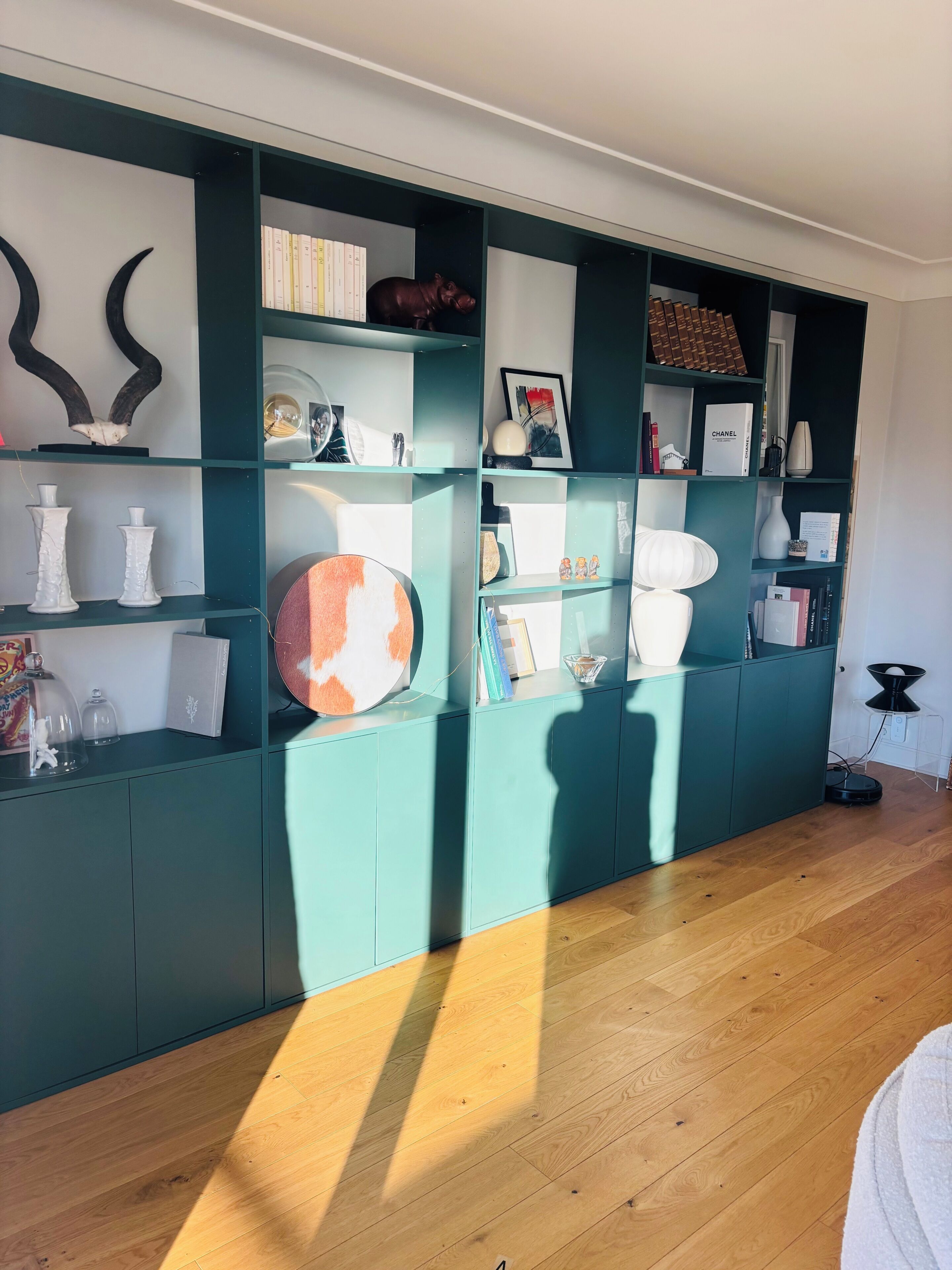 Uma estante verde-água com diversos objetos decorativos e livros.