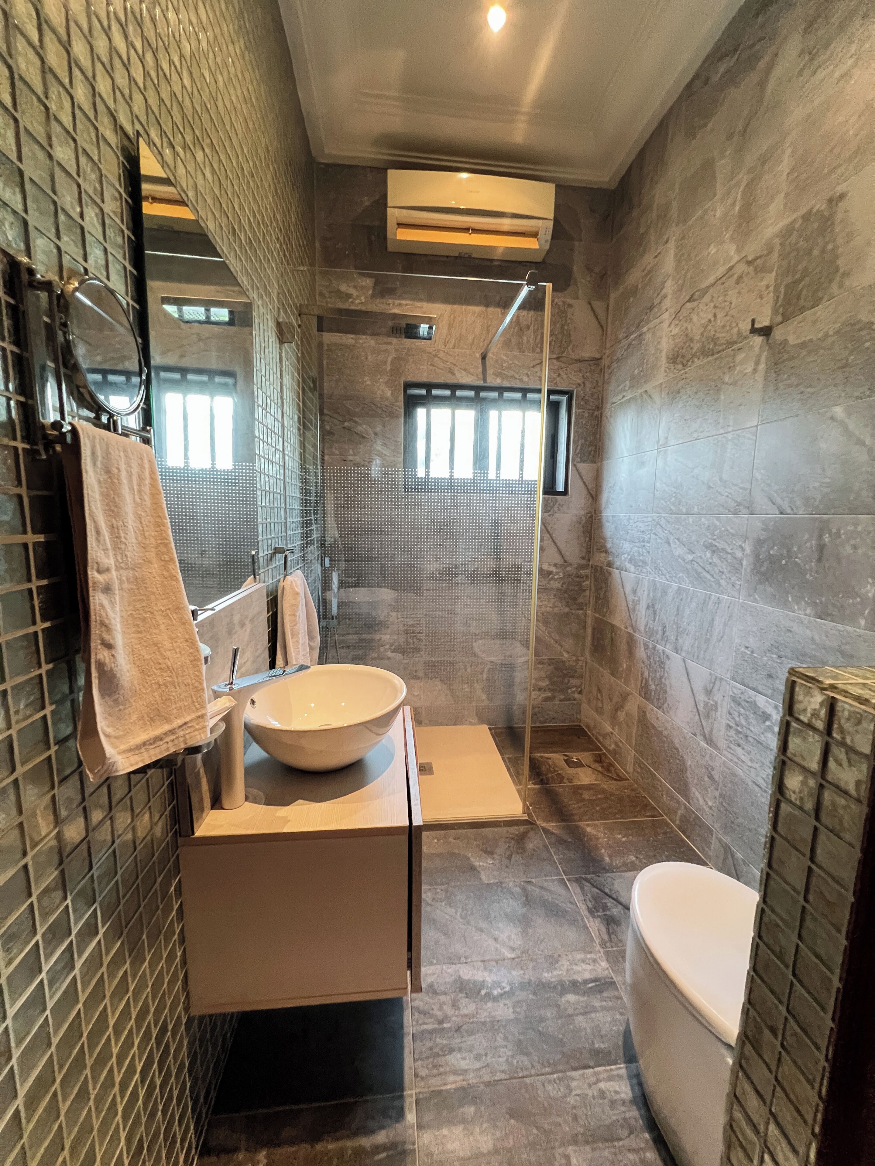 A modern bathroom with a large mirror, a sink, a toilet, and a shower area.