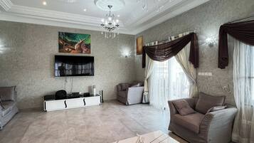 Appartement Deluxe, balcon | Coin séjour | TV connectée de 75 pouces avec chaßnes par satellite
