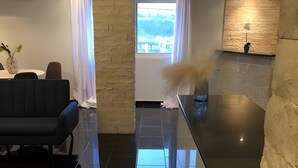 A modern kitchen with a black countertop, a stone accent wall, and a view through a window. - Apartment 'Superior' with Mountain View, Wi-Fi and Air Conditioning (Paleokastritsa)