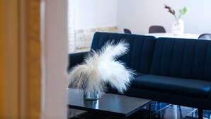 A modern interior with a dark blue sofa, a glass coffee table, and a vase with white feathers. - Apartment 'Superior' with Mountain View, Wi-Fi and Air Conditioning (Paleokastritsa)