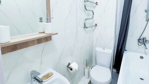 Un baño con lavamanos, inodoro y zona de ducha.