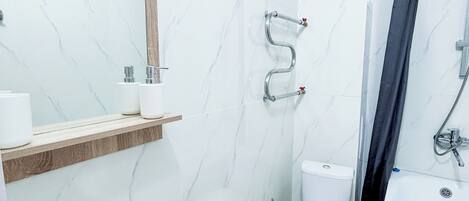 Un baño con lavamanos, inodoro y zona de ducha.