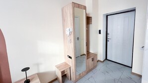 Una habitación con un armario de madera, un banco, una puerta y un espejo.