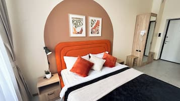 Habitación de hotel con cama, mesita de noche, lámpara y dos cuadros en la pared.