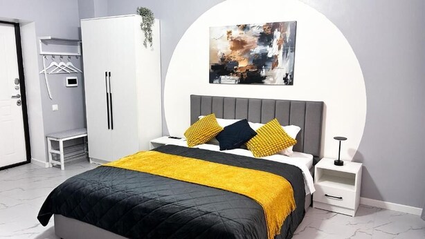 Un dormitorio con cama, mesita de noche y un cuadro abstracto colgado en la pared.