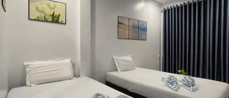 Habitación de hotel con dos camas, una ventana con cortinas y obras de arte en las paredes.