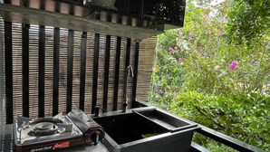 A gas stove, a sink, and a wooden fence with a garden view. - Mother's House (Battambang)