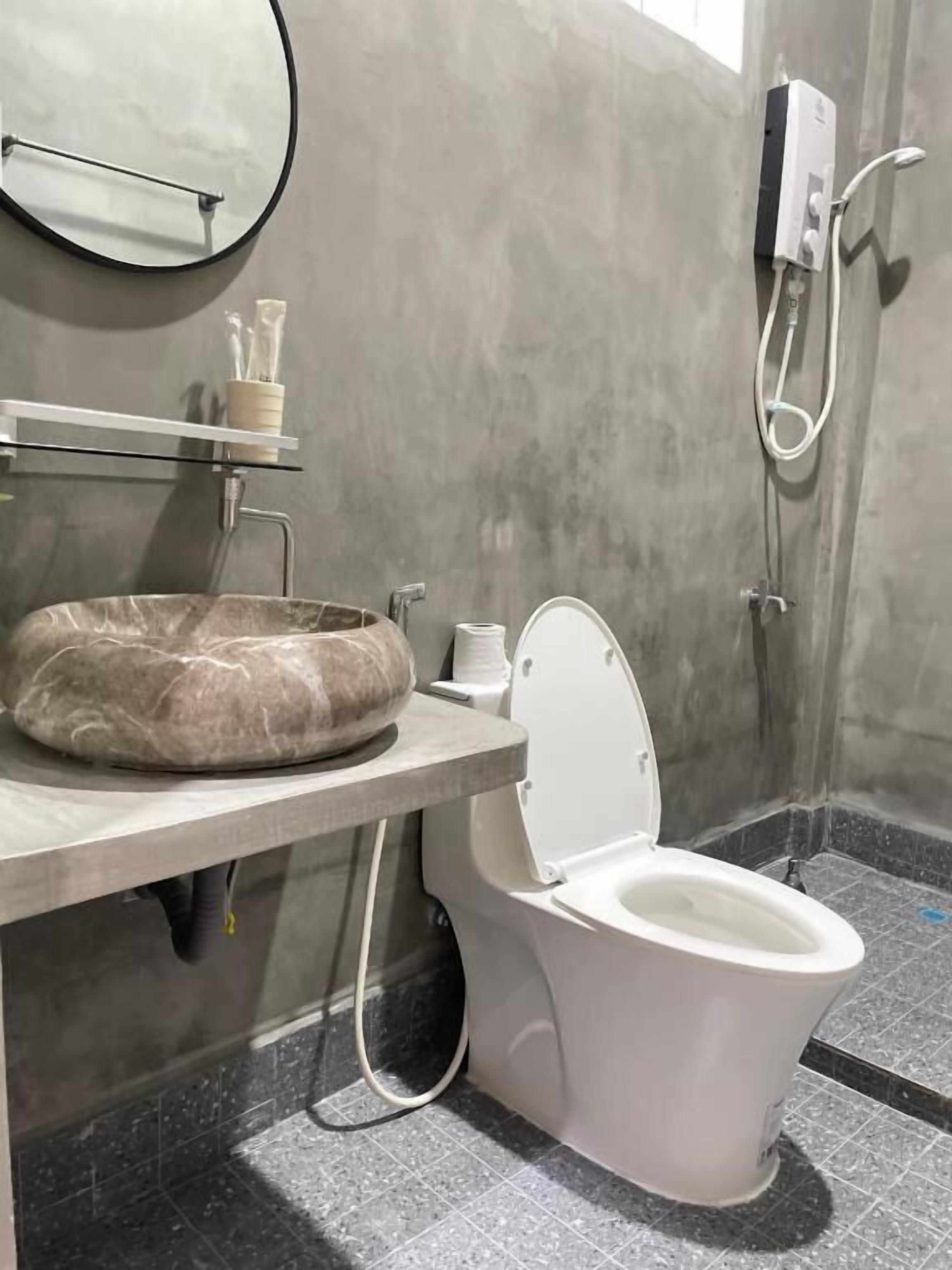 Un baño con lavamanos de mármol, inodoro, espejo y ducha.