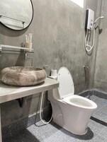 Un baño con lavamanos de mármol, inodoro, espejo y ducha.