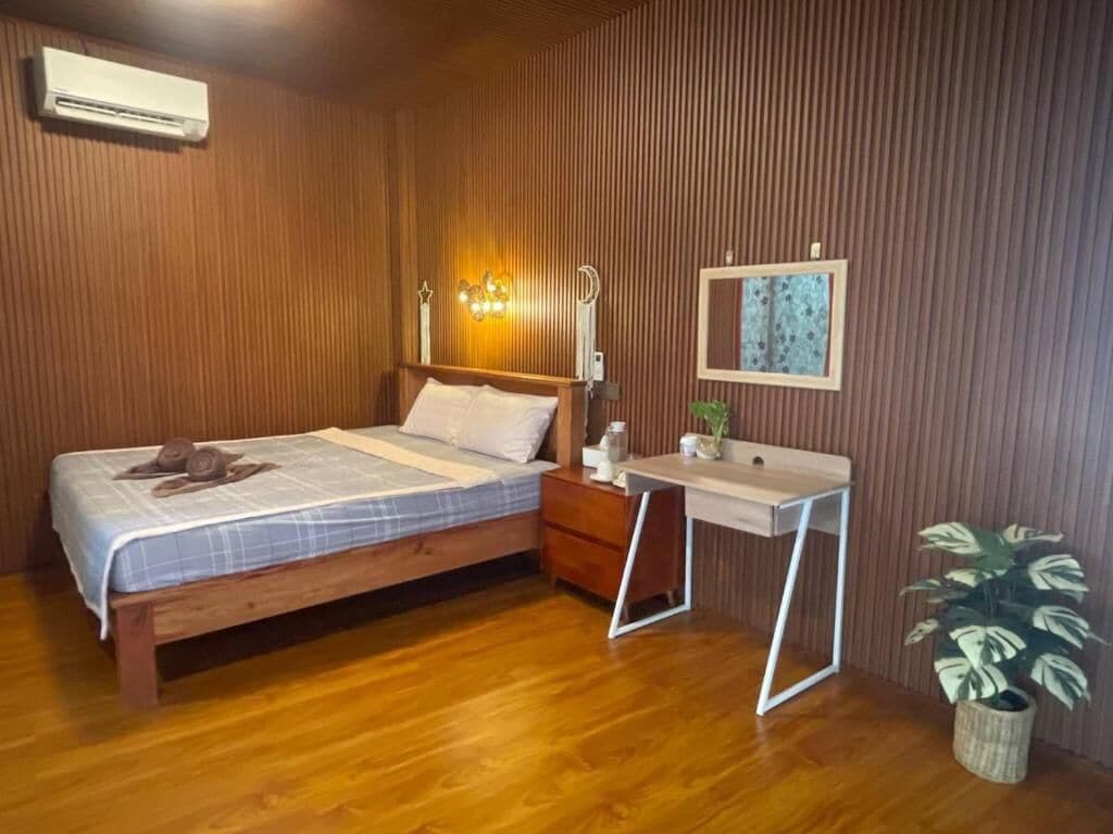 Un dormitorio con una cama de madera, una mesita de noche y un pequeño escritorio con una planta.