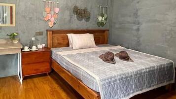 A bedroom with a wooden bed, a bedside table, a small desk, and a mirror.