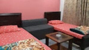 A room with a bed, a sofa, a small table, and a window with curtains.