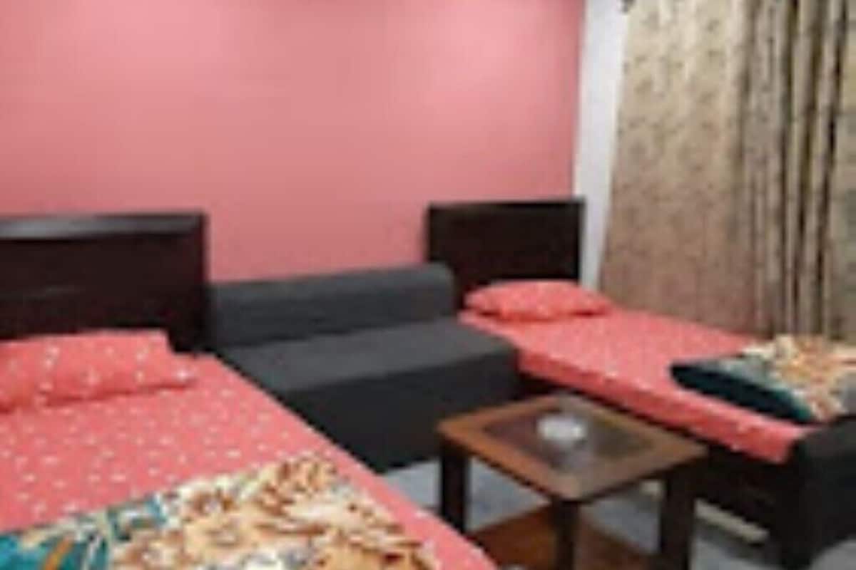 A room with a bed, a sofa, a small table, and a window with curtains.