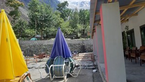 A terrace with outdoor seating, a stone wall, and a mountain view.