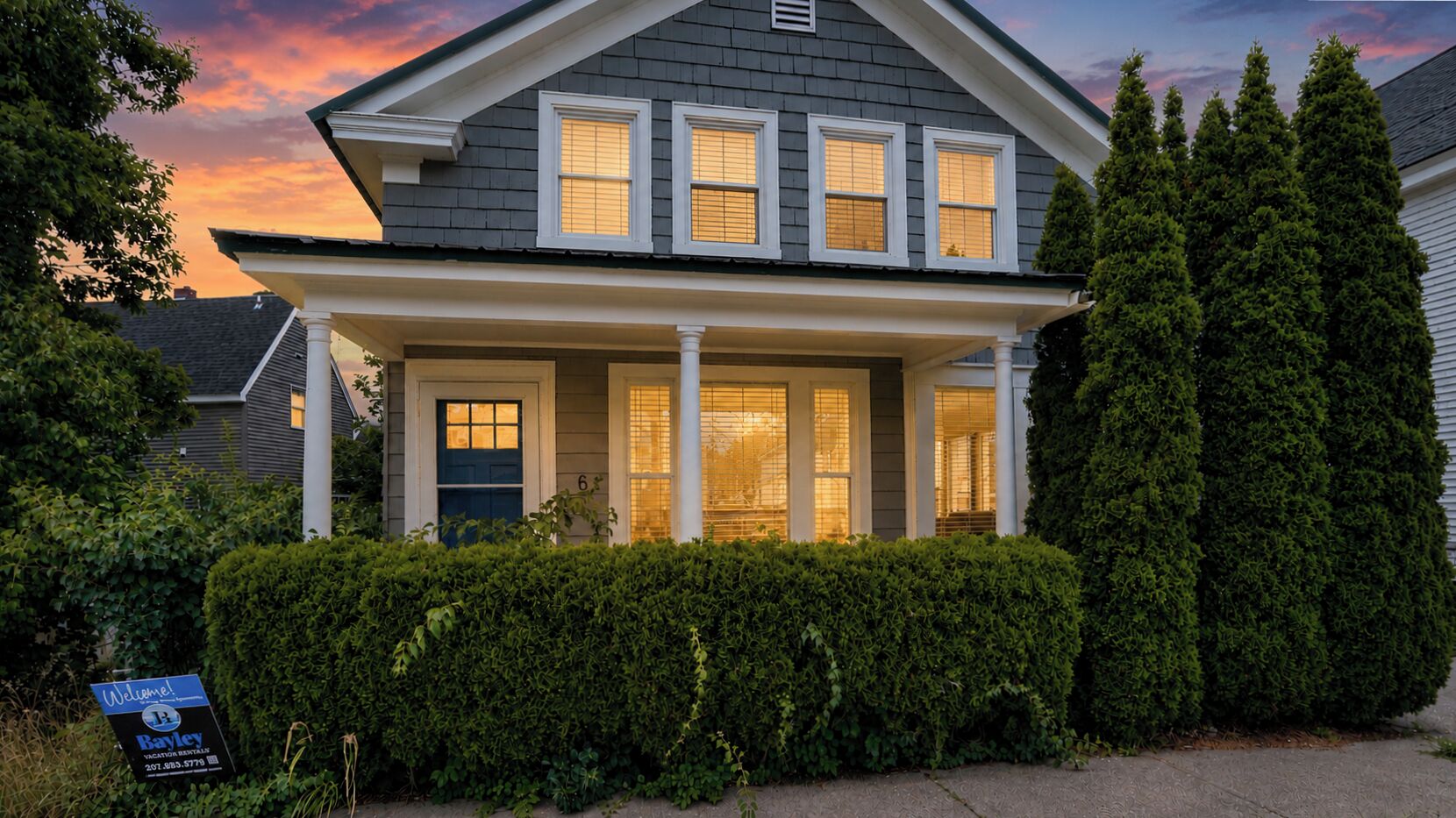 A two-story house with a front porch, a mailbox, and a 'Welcome' sign.