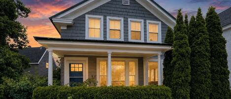 A two-story house with a front porch, a mailbox, and a 'Welcome' sign.