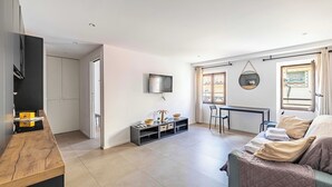 Ein modernes Wohnzimmer mit einer Couch, einem Fernseher, einer Holztresen und einem Essbereich mit Tisch und Stühlen.
