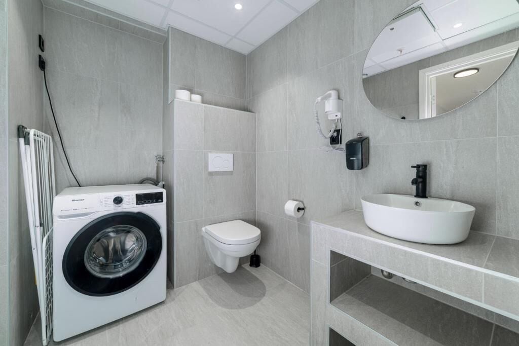 Une salle de bain moderne équipée d’un lave-linge, de toilettes et d’un lavabo intégrés.