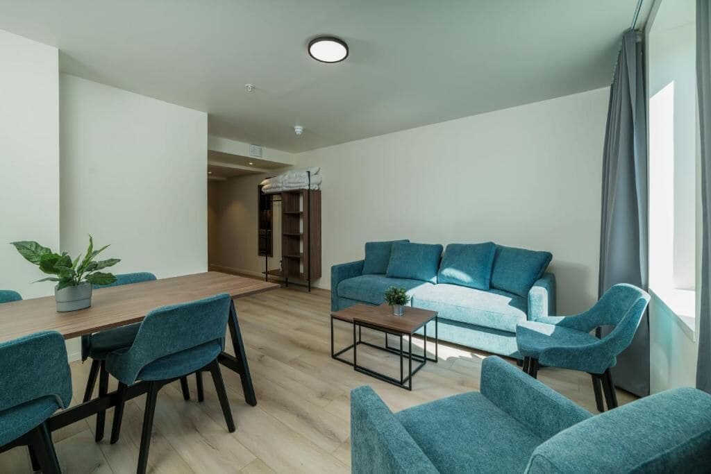 A modern living room with a sofa, chairs, a coffee table, and a dining table.