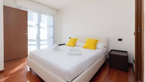 Una habitación de hotel con cama, mesita de noche y piso de madera.