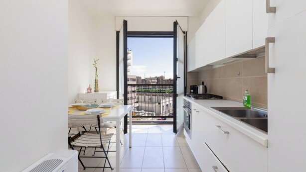 Una cocina estrecha con comedor, vista a través de una puerta abierta y un balcón.