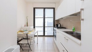 Una cocina compacta con comedor, una puerta corredera de marco negro y una encimera blanca.