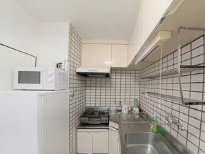 Una cocina compacta con microondas, estufa y lavamanos.