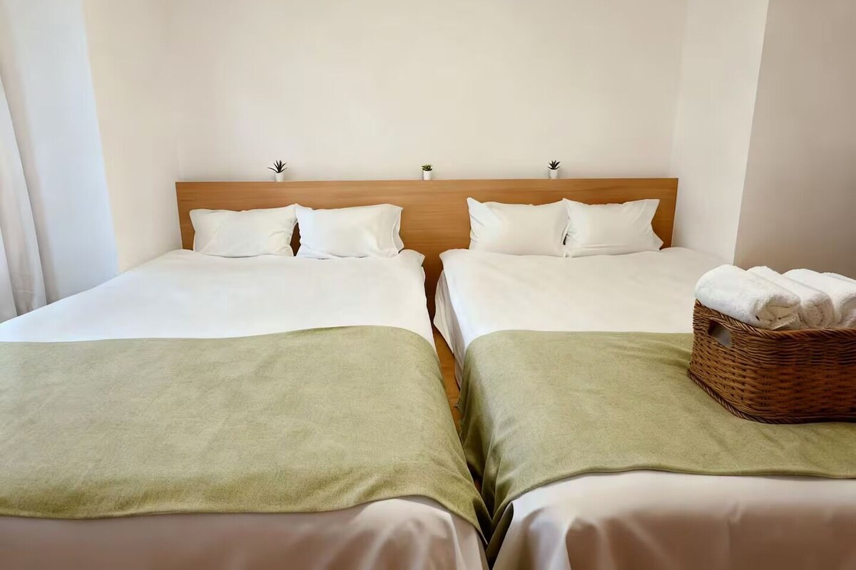 A twin room with two beds, a wooden headboard, and a wicker basket with towels.