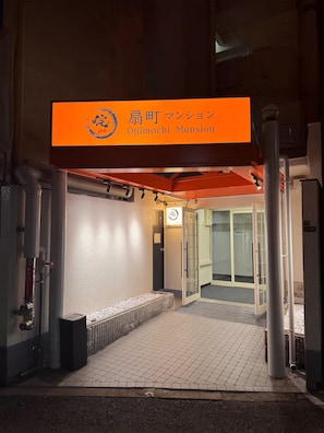 Una entrada de edificio con un letrero que dice 'Ojimachi Mansion'.