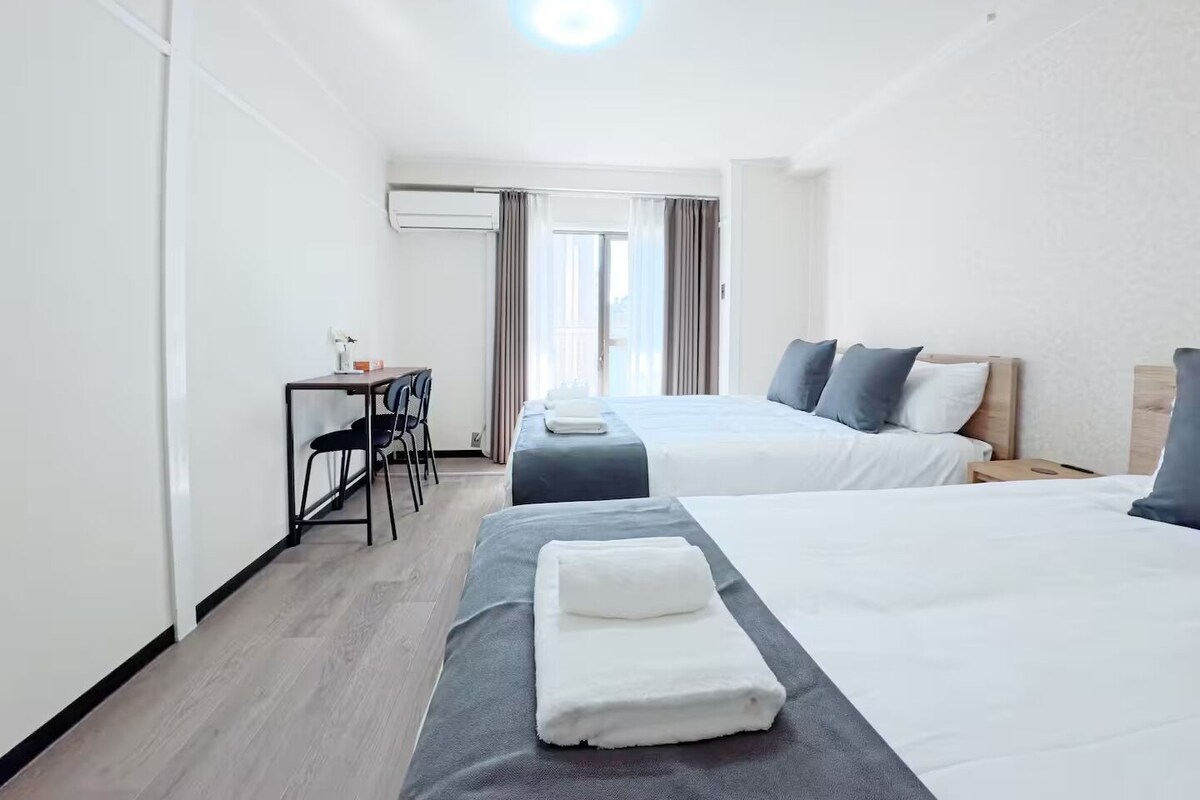 A hotel room with two beds, a desk, and a chair.