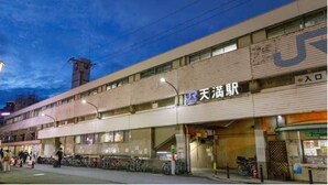 Un edificio de varios pisos con un gran letrero que dice '天満橋' y una zona de estacionamiento para bicicletas enfrente.