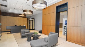 Eine moderne Lobby mit einer Rezeption, grauen Sofas, einem Couchtisch und einem Zugang zur Post.