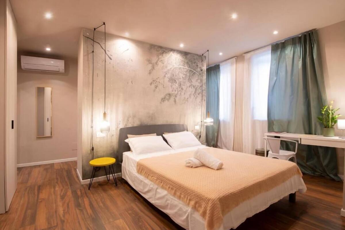 A modern hotel room with a large bed, a desk, and a chair.