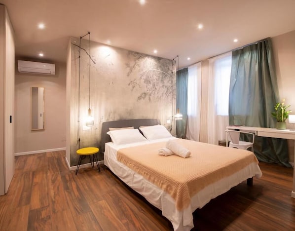 A modern hotel room with a large bed, a desk, and a chair.