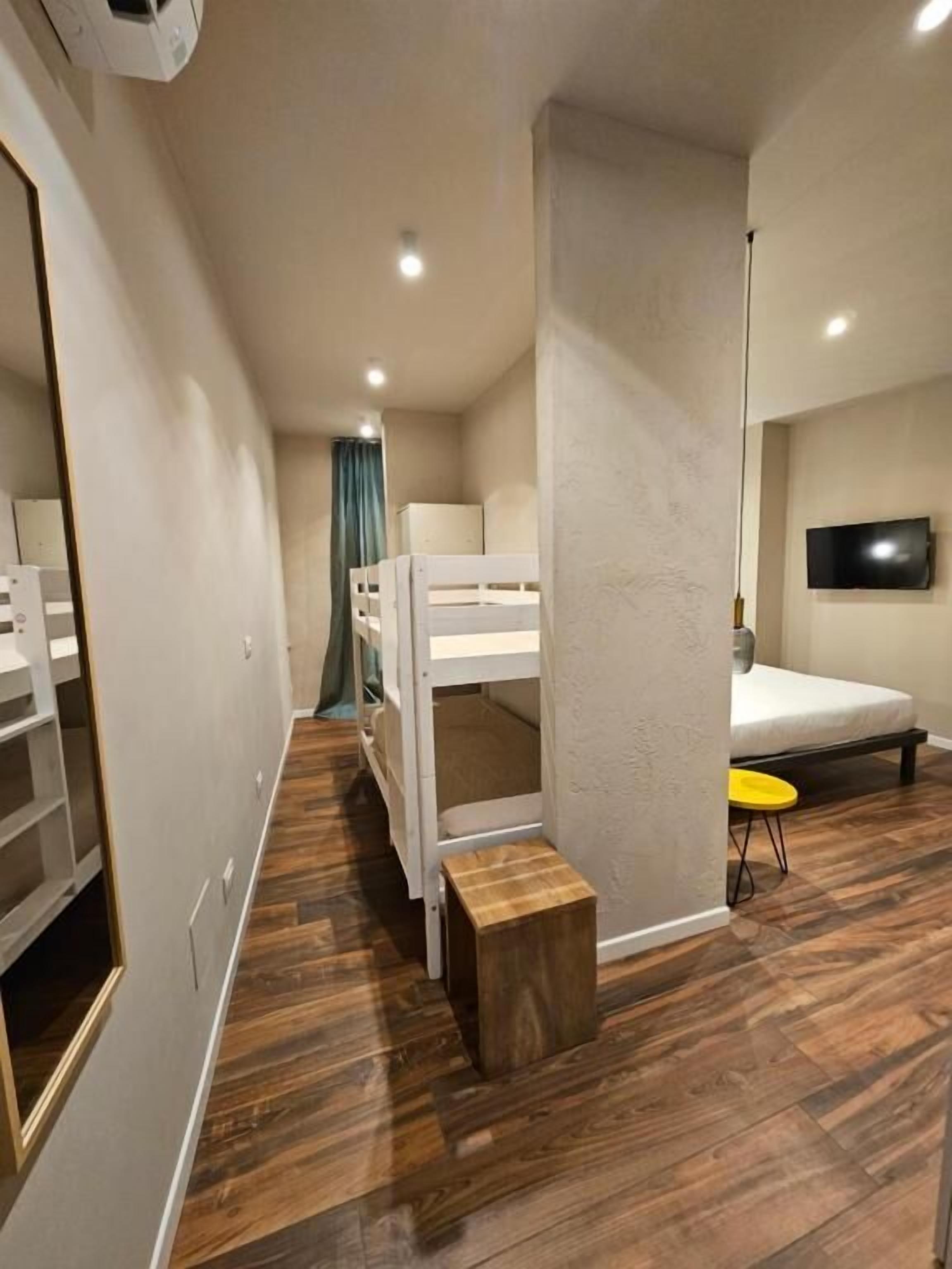 A modern room with bunk beds, a TV, a small table, and a wardrobe.