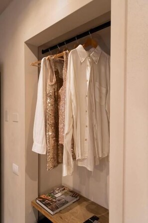 A closet with hanging clothes and a magazine on a shelf. - San Benedetto Rooms (Crema)
