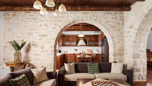 A cozy living room with a stone wall, wooden furniture, and a chessboard. - Your Villa (Chania)