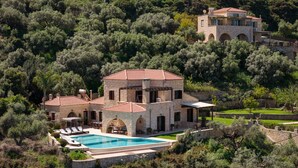 A stone villa with a swimming pool, surrounded by dense trees and a hilly landscape. - Your Villa (Chania)