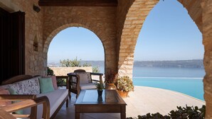 A stone-arched outdoor seating area with a view of the sea. - Your Villa (Chania)