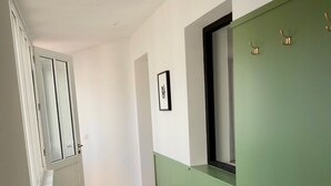 A narrow hallway with a bench, a radiator, and a green wall with a window. - Maison Vicoli, completely new & renovated, Les Portes en Ré, Île de Ré! (Les Portes-en-Ré)